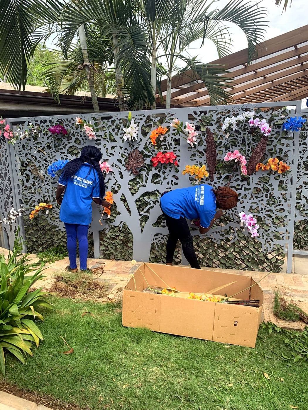 Two White Wall staff dressing a flower wall