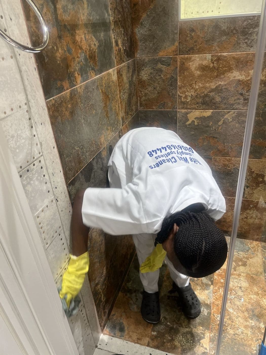 A White Wall cleaner scrubbing shower tiles